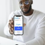 A man holding a smartphone displaying the Froala editor's homepage.