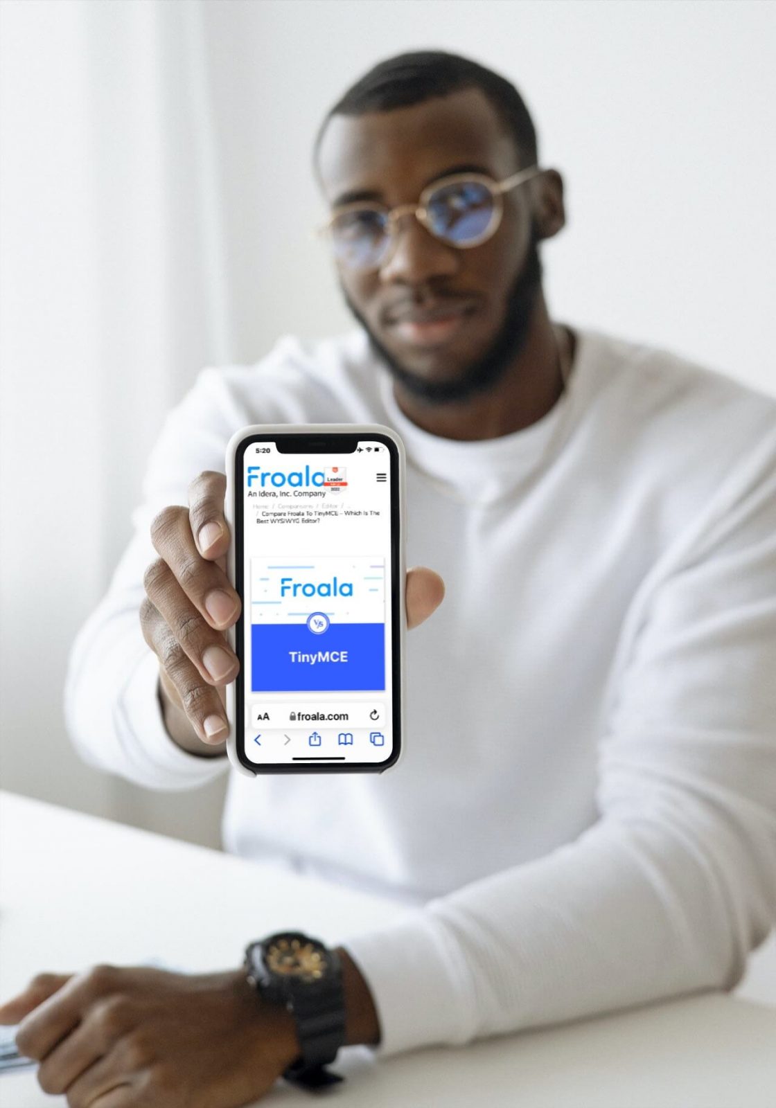 A man holding a smartphone displaying the Froala editor's homepage.