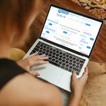 a person using a laptop computer sitting on top of a table