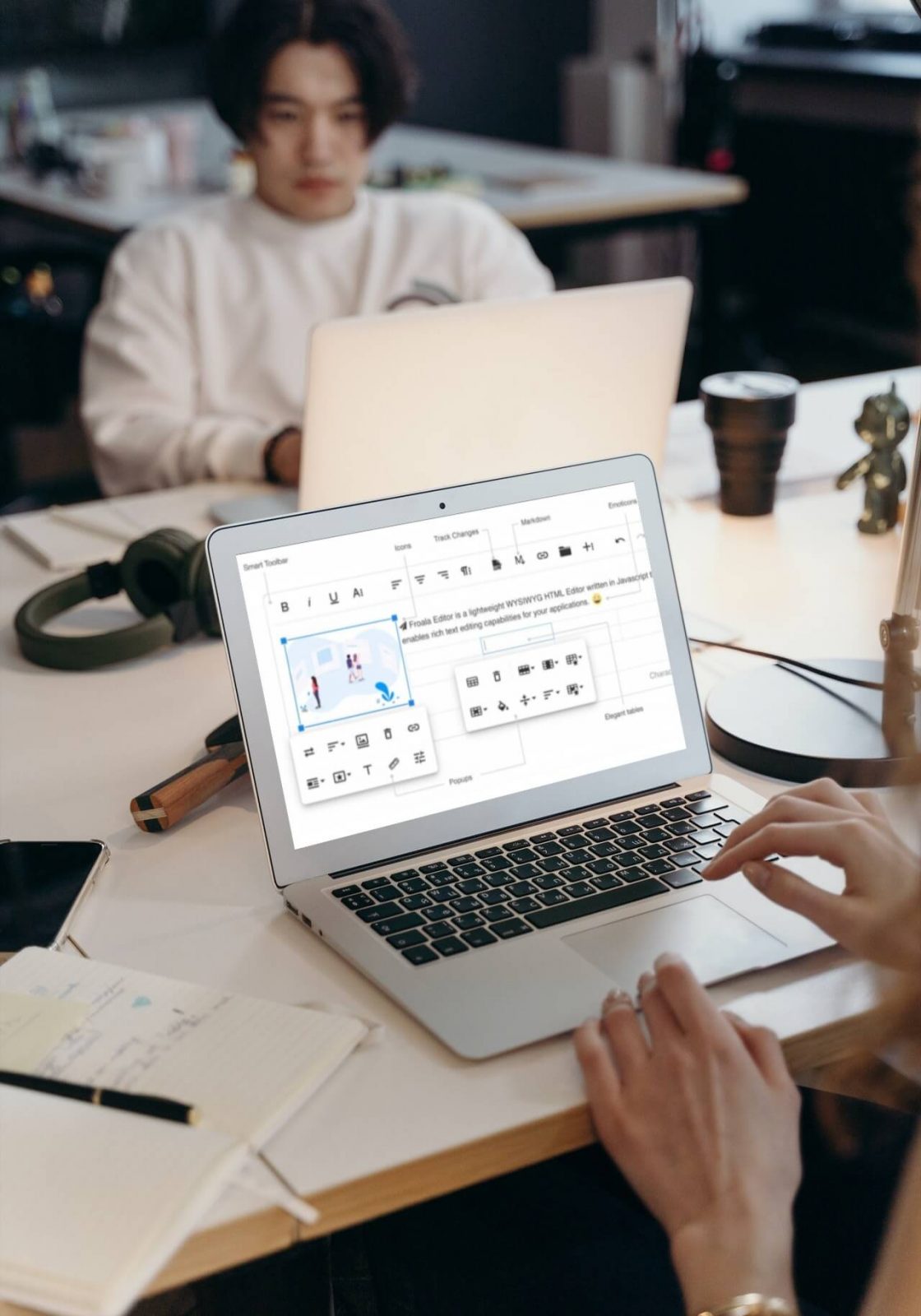 A person working on a laptop with a WYSIWYG editor open on the screen.
