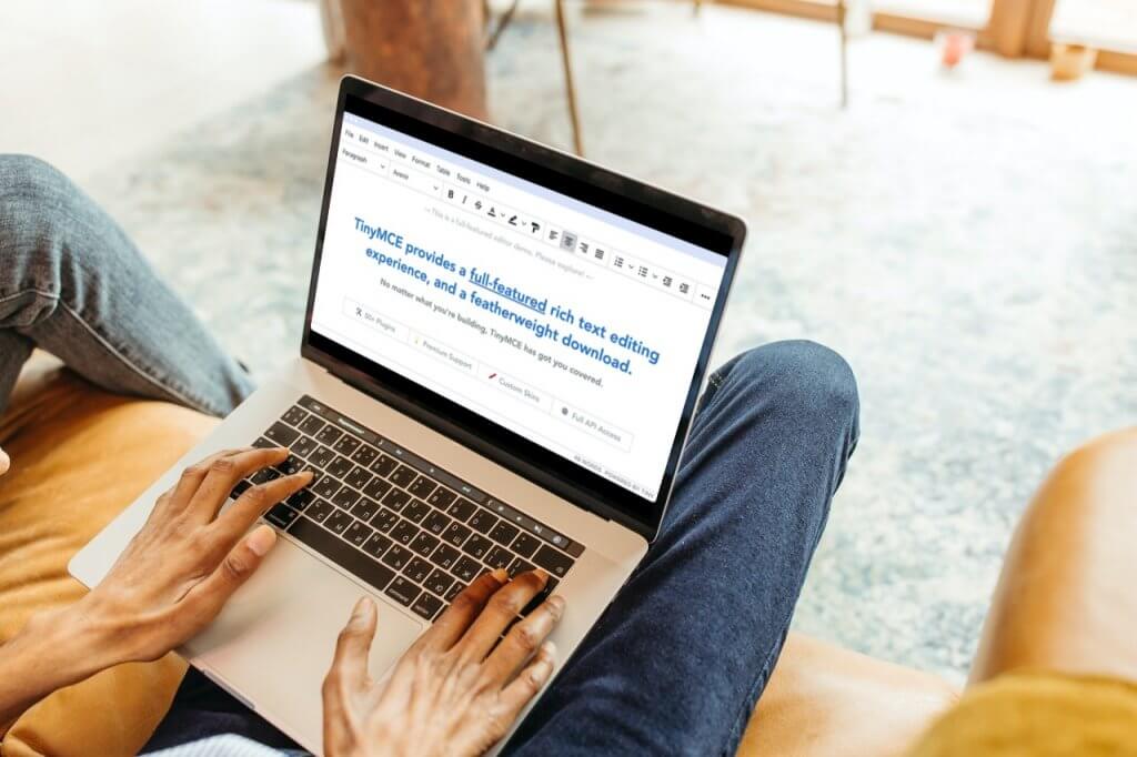 Someone using a laptop with the TinyMCE text editor page on the screen.